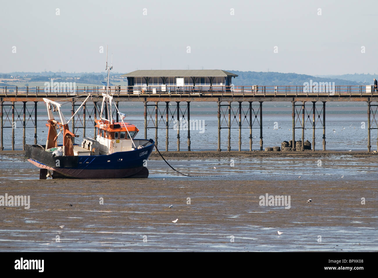 A fishing boat beached at low tide near the pier in Southend on Sea in