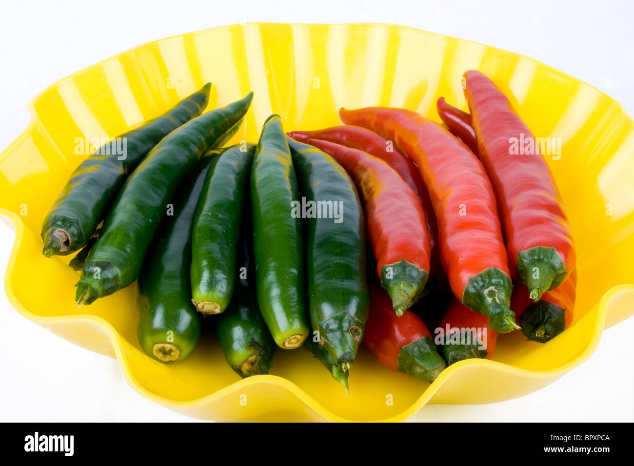 Red and green chili peppers in the yellow plate Stock Photo - Alamy