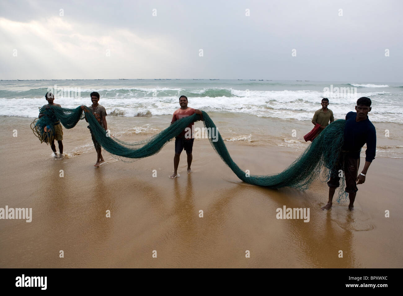 Group of Indian fishermen on the beach take fishing net after washing it in  the sea at the fishing village in Puri Stock Photo - Alamy