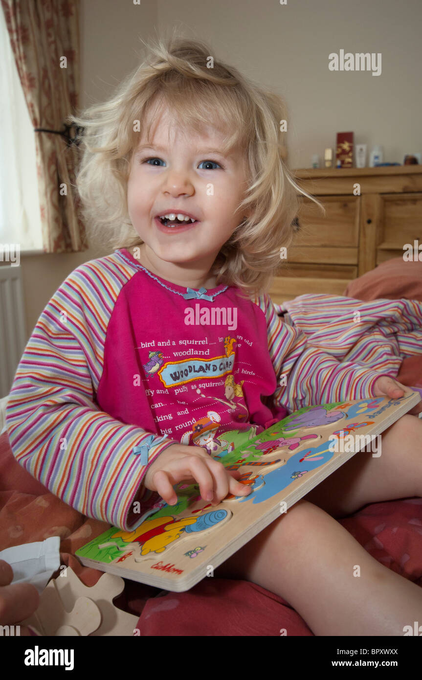 young three year old child doing jigsaw puzzle in bed with hand of