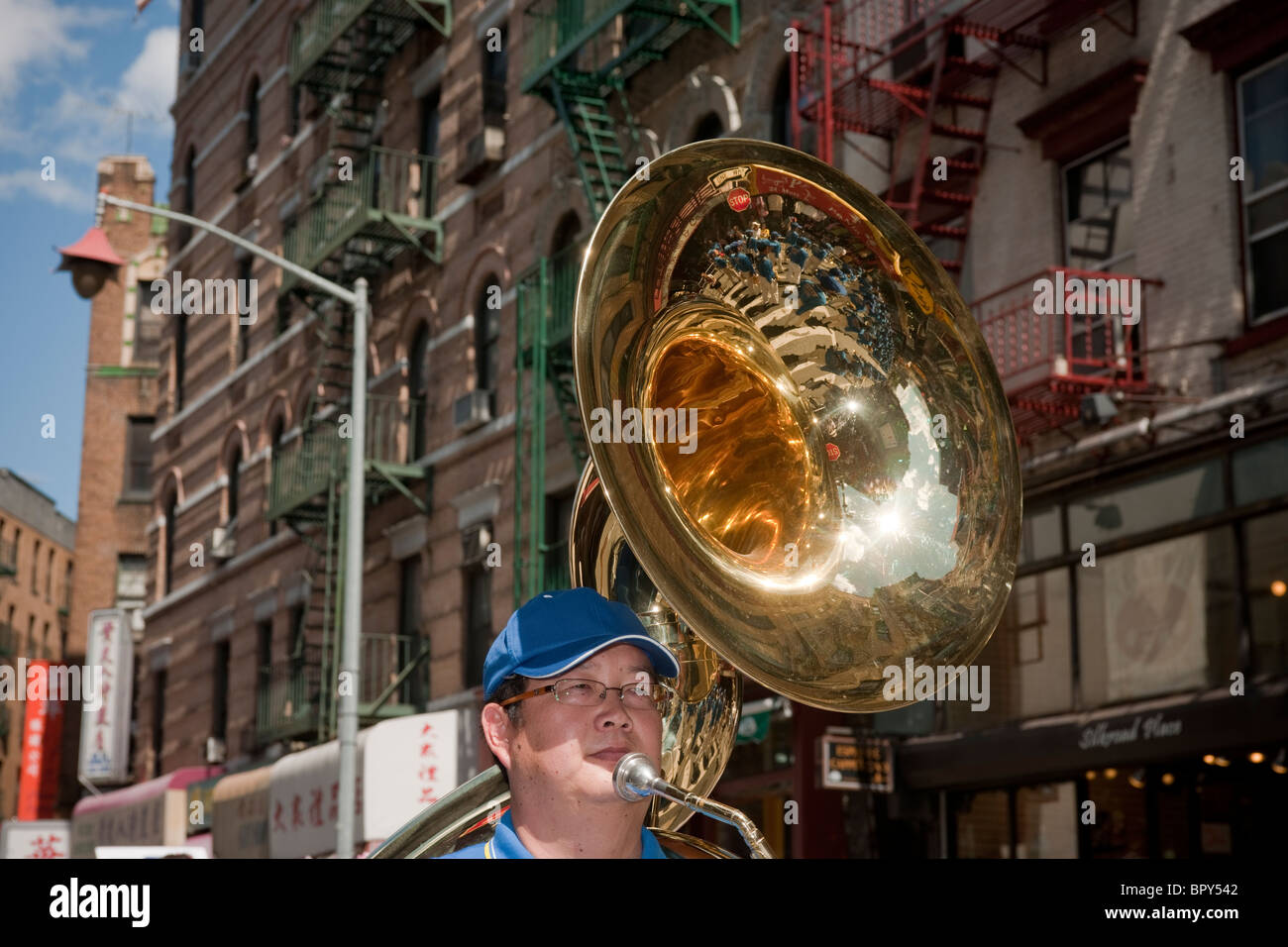 A member of a marching band playing his sousaphone marches through the streets of Chinatown in New York Stock Photo