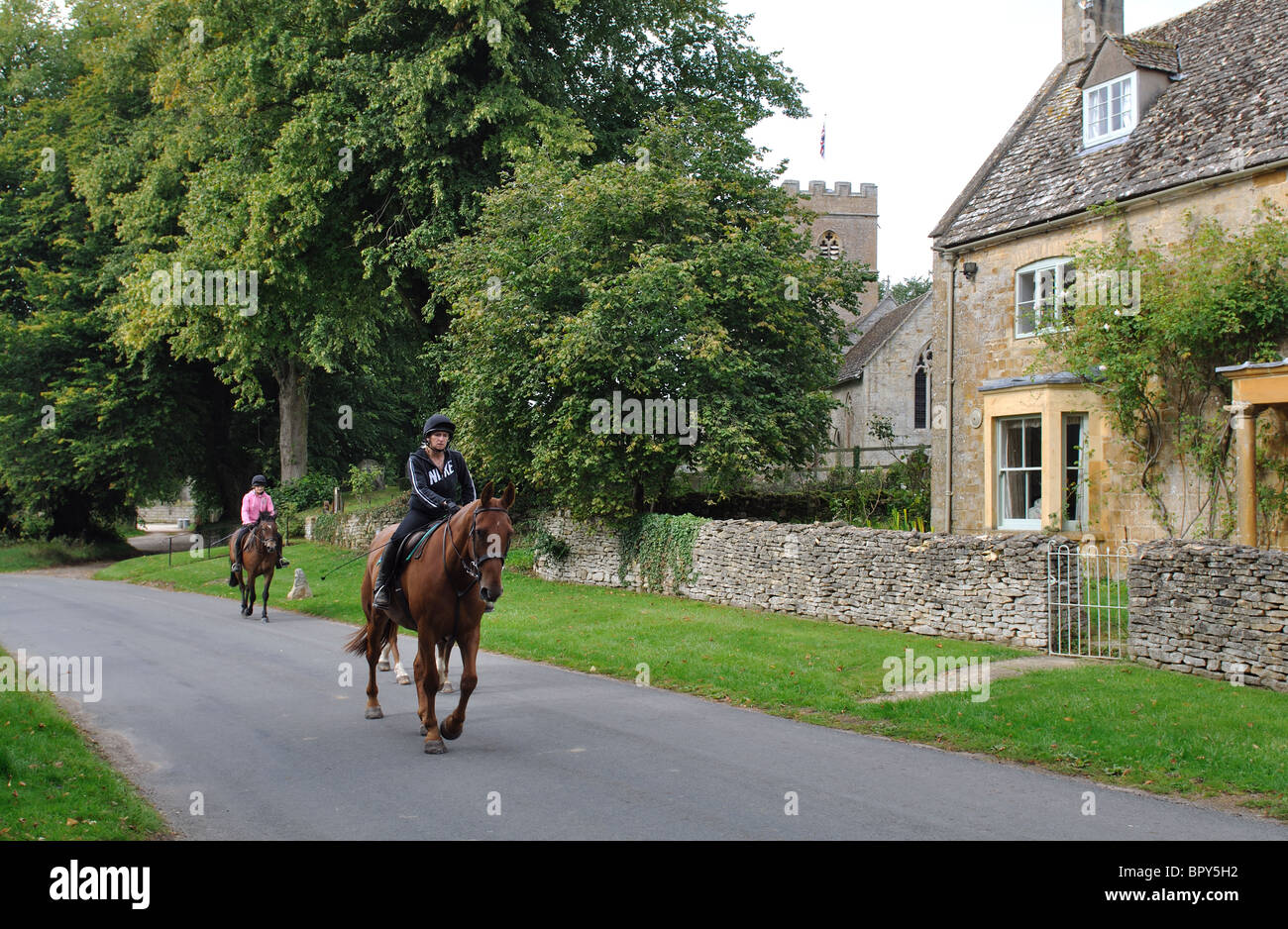 Horse riders in Evenlode village, Gloucestershire, England, UK Stock