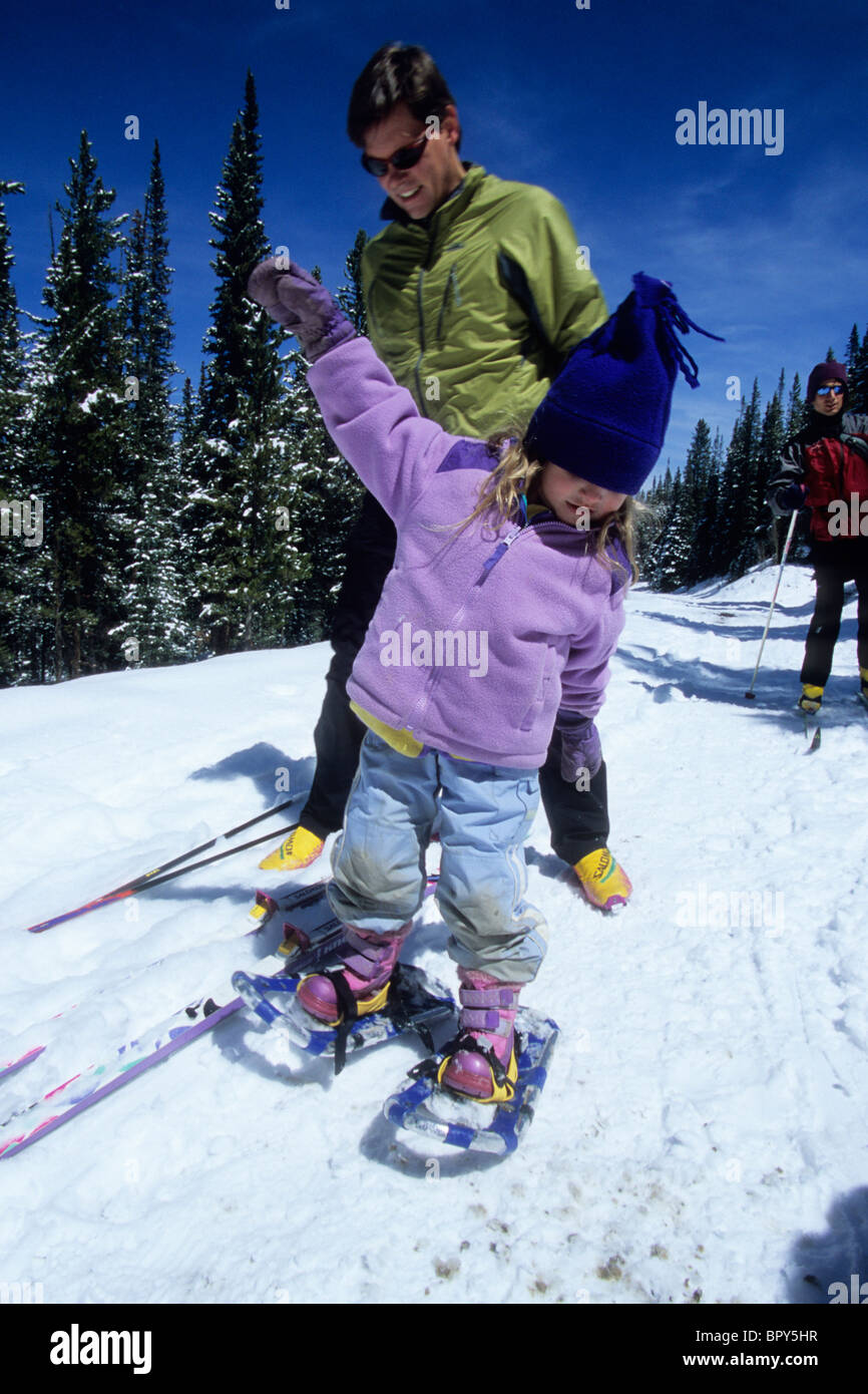 A father helps his daughter snowshoe, on a trail outside Breckenridge, CO Stock Photo