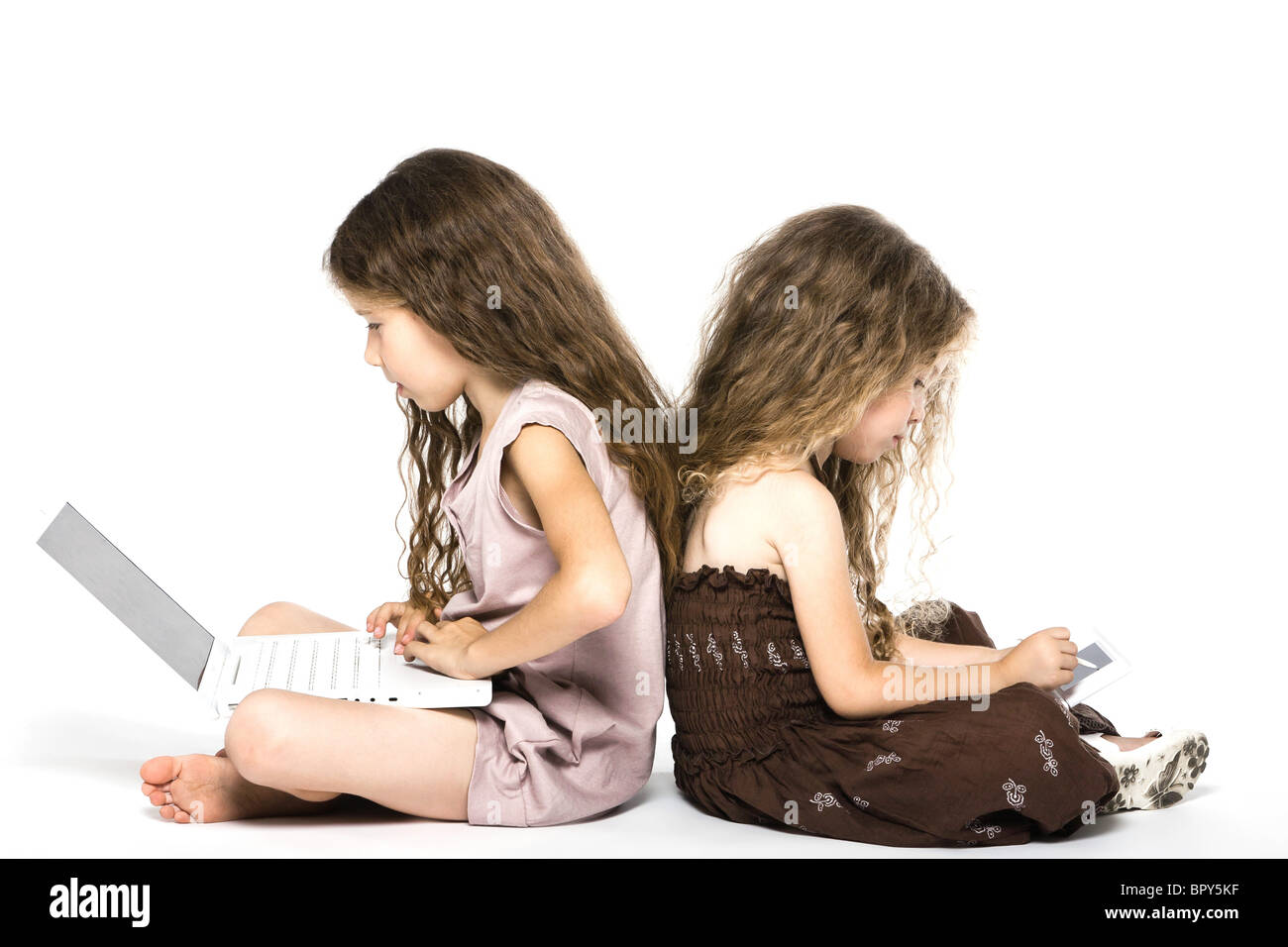 caucasian little girls playing game console back to back isolated studio on white background Stock Photo