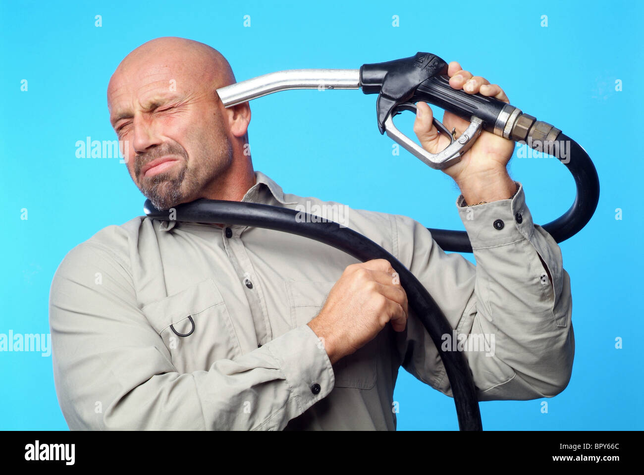 Man holding a petrol nozzle against his head Stock Photo