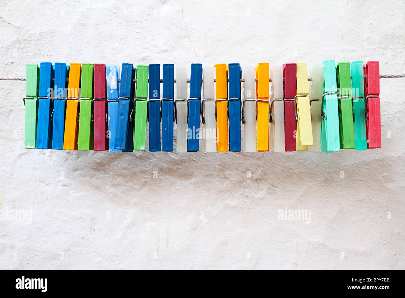 Row of plastic clothes pegs against whitewashed wall Stock Photo