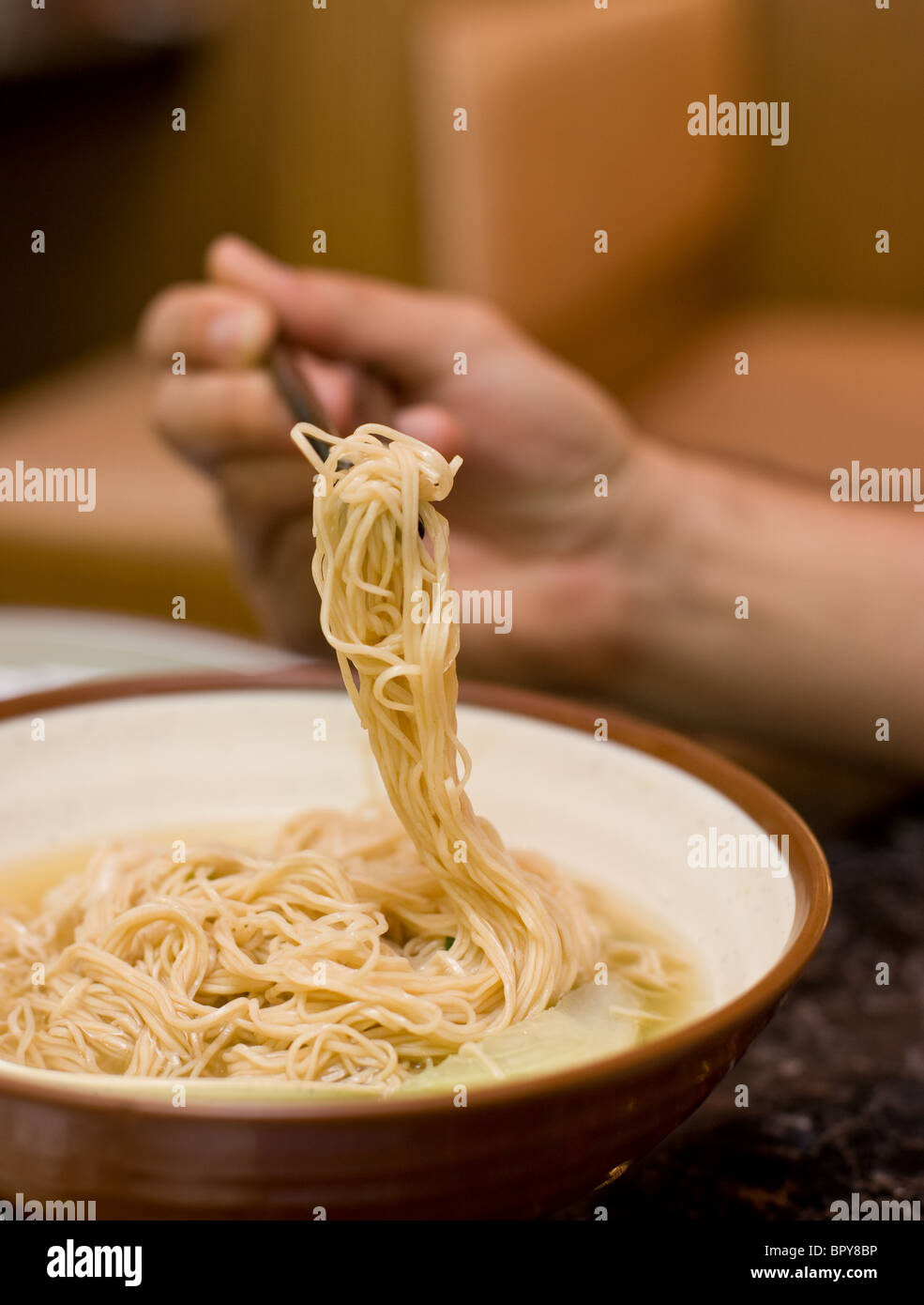 Shrimp wonton soup eaten with spoon and chopsticks at Chinese restaurant Stock Photo