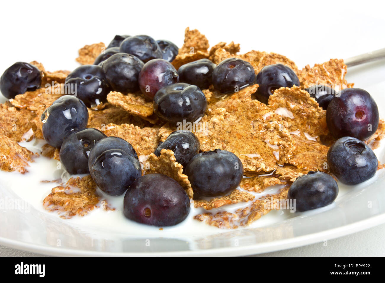 Breakfast Cereal Medley of bran flakes, blueberries, honey and milk. Stock Photo