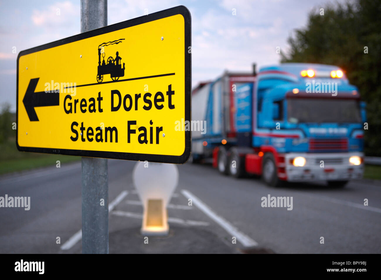 Sign pointing towards the Great Dorset Steam Fair and a lorry being driven home on the final day, Dorset, England, UK Sept 2010 Stock Photo