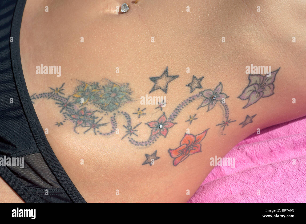 Tattoo and jewel in belly button Stock Photo - Alamy