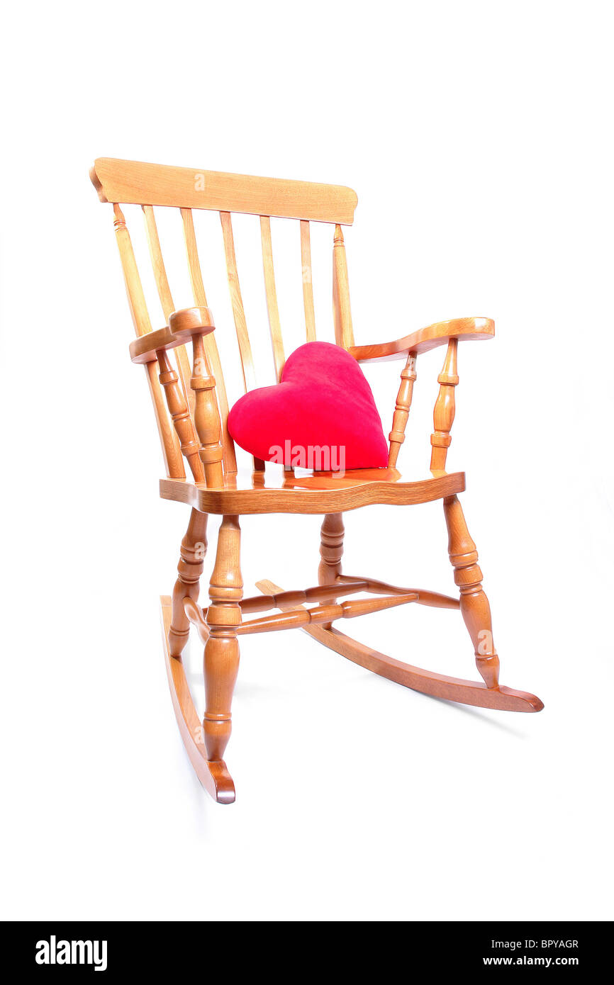 Wooden rocking chair with red heart shaped pillow over white background Stock Photo