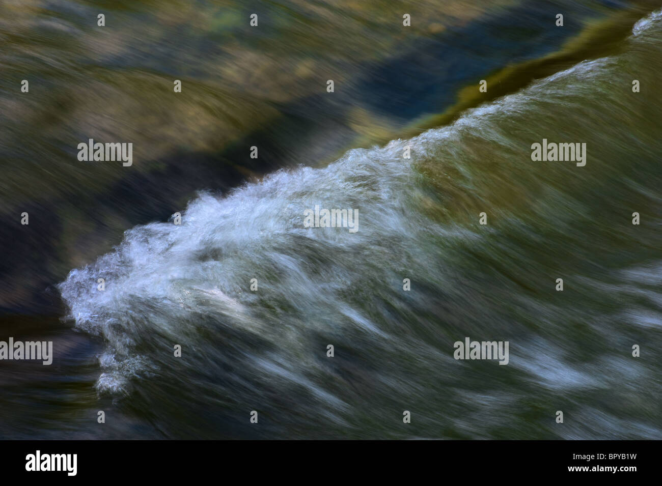 small wave in a river created by submerged rocks. Image taken with slow speed so as to show the flow of the water better Stock Photo