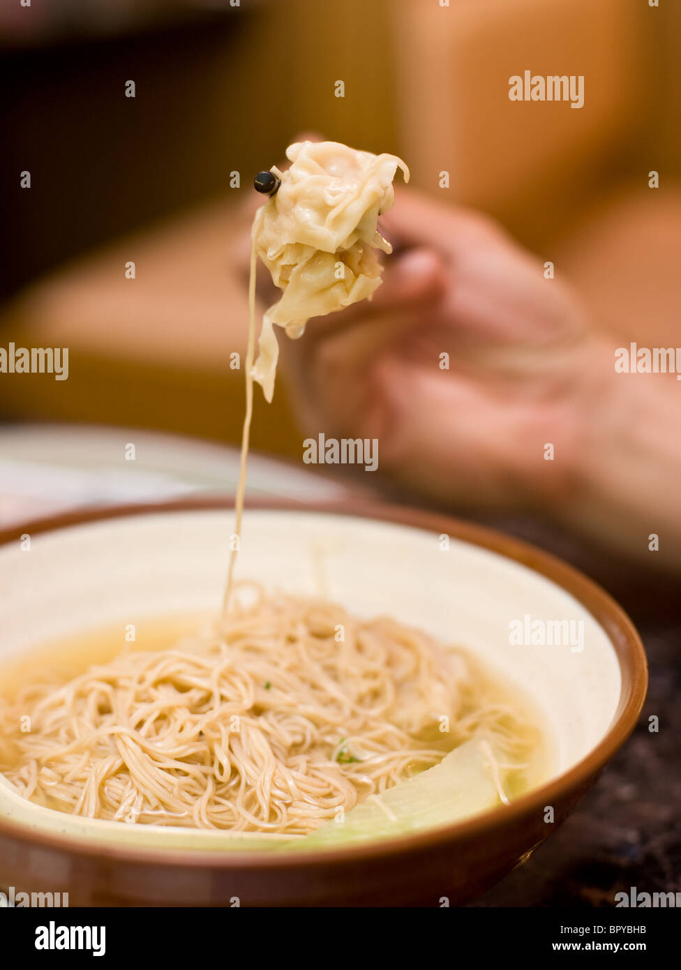 Shrimp wonton soup eaten with spoon and chopsticks at Chinese restaurant Stock Photo