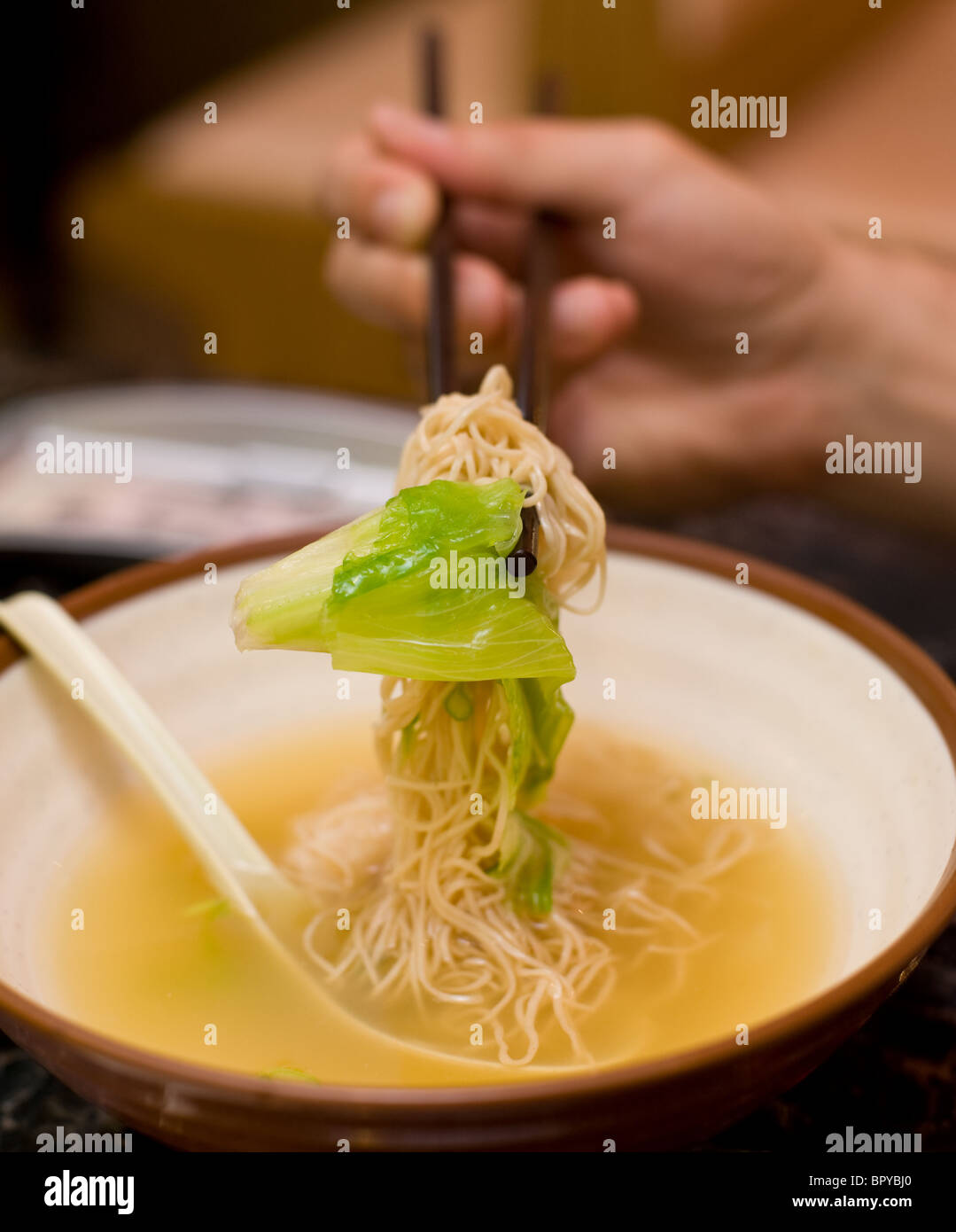 Shrimp wonton soup eaten with spoon and chopsticks at Chinese restaurant Stock Photo