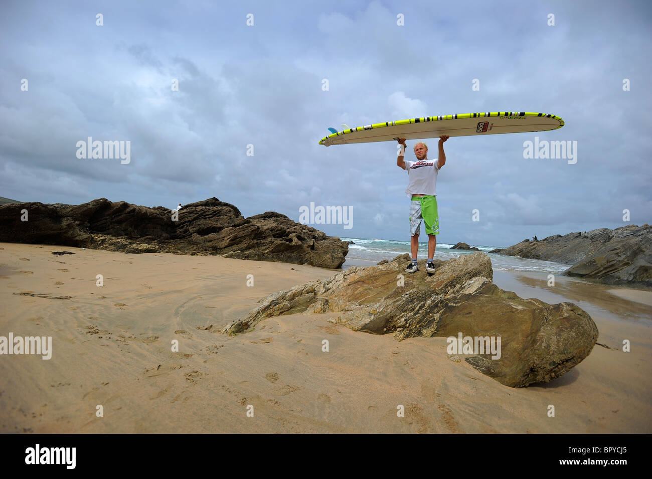 A surfer, Ben Howey, holding a longboard surfboard on the beach at Fistral, Newquay, the UK's surfing capital, in Cornwall Stock Photo