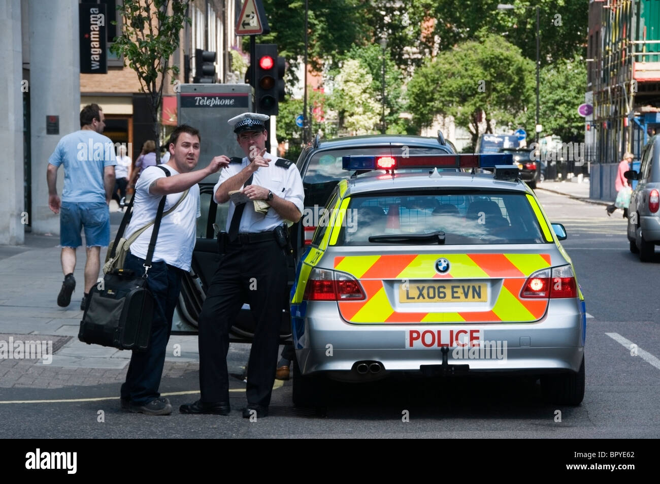 Metropolitan Police helping tourist, with his hand pointing direction on a street, West End, London, England, UK, Europe, EU Stock Photo