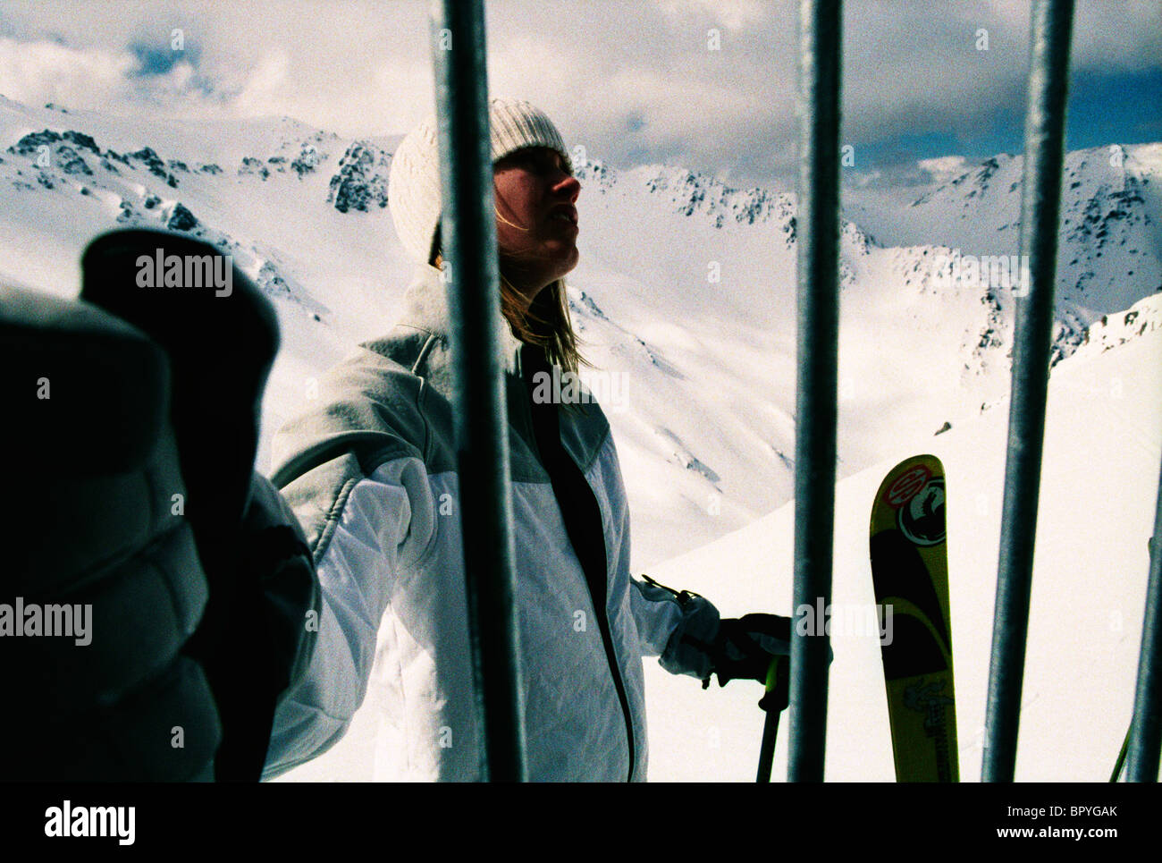 A woman stands behind a fence at a ski resort. Stock Photo