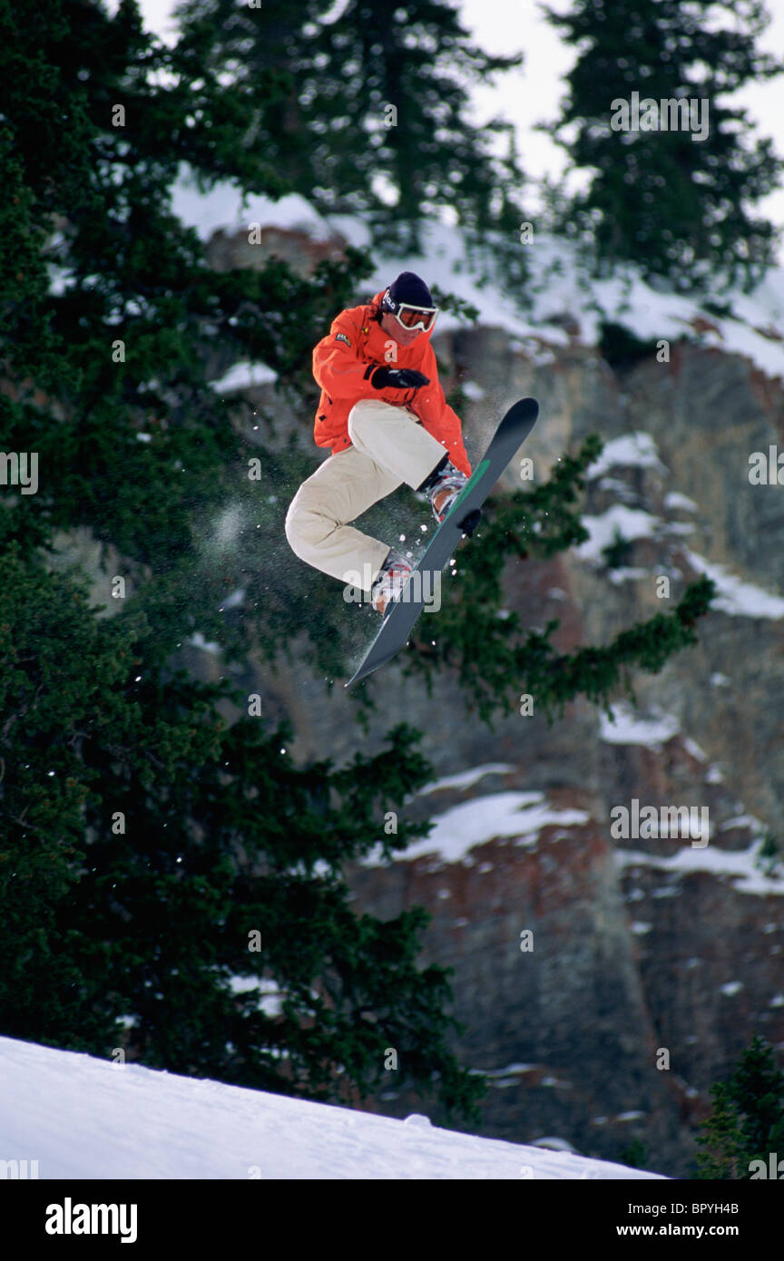 Female snowboarder catches some air in the backcountry Stock Photo
