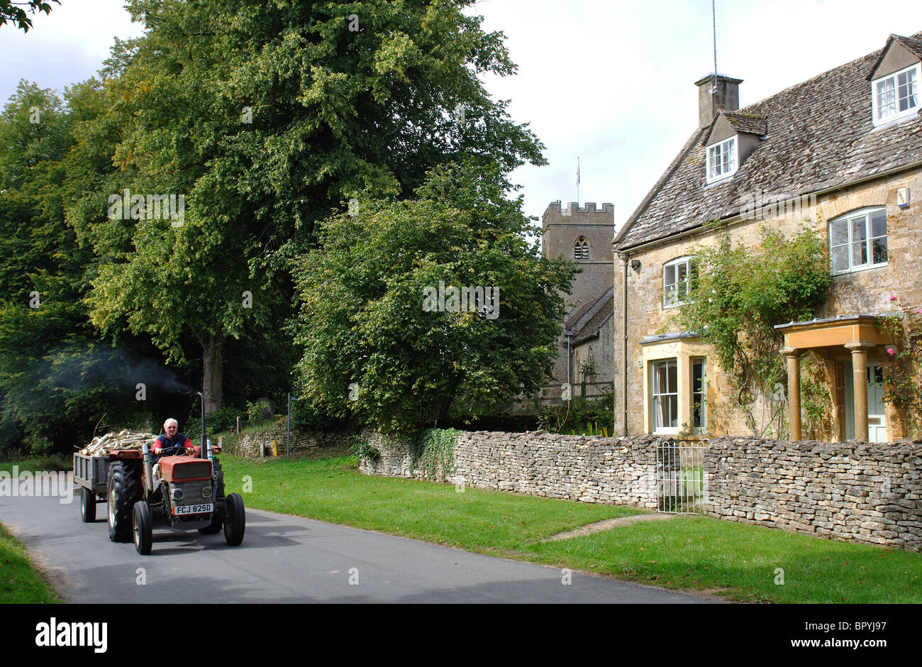 Tractor passing through Evenlode village, Gloucestershire, England, UK