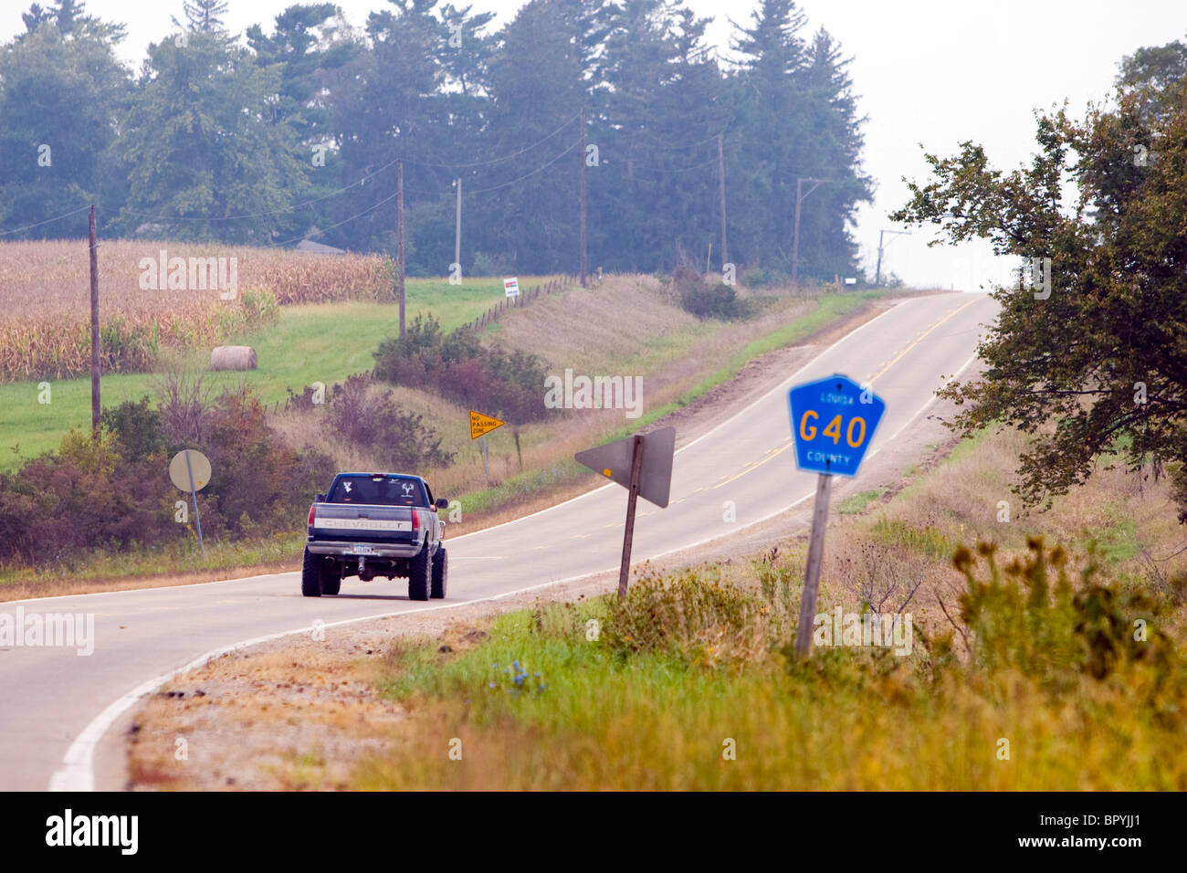 A pickup truck with giant tires heads down a county highway in Iowa. Stock Photo