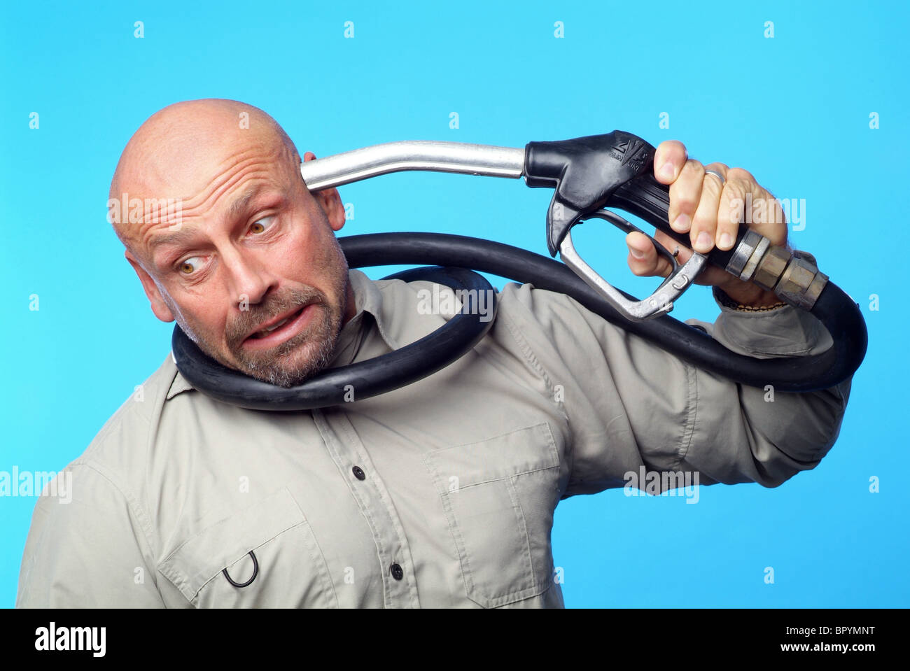 Man holding a petrol nozzle against his head Stock Photo