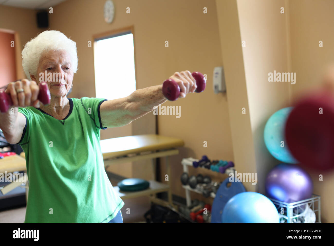 senior woman exercising at gym w/ weights Stock Photo