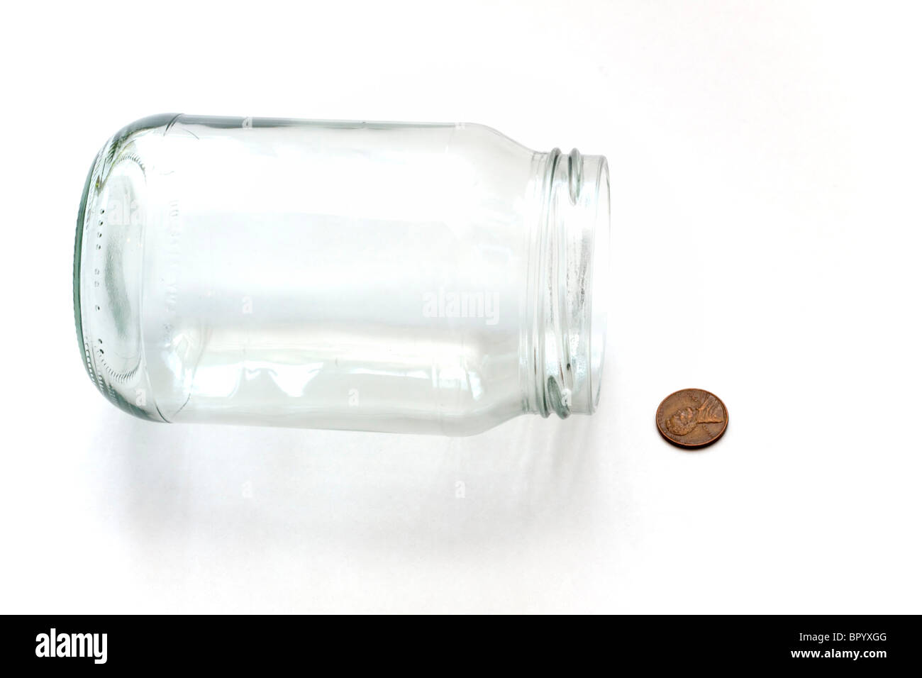 Empty money jar with spilled penny Stock Photo