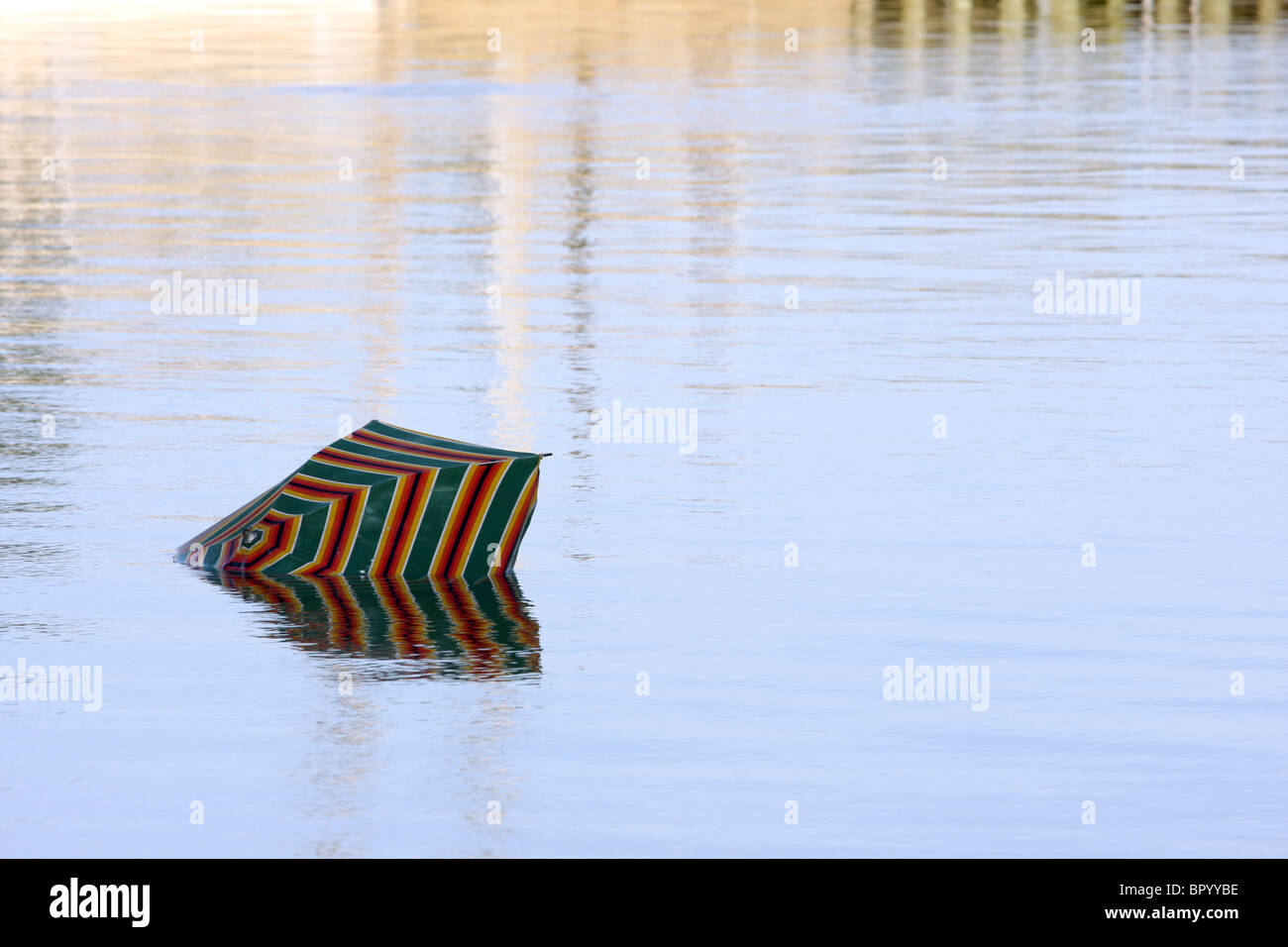 Broken umbrella in ocean water with sunset light Stock Photo - Alamy