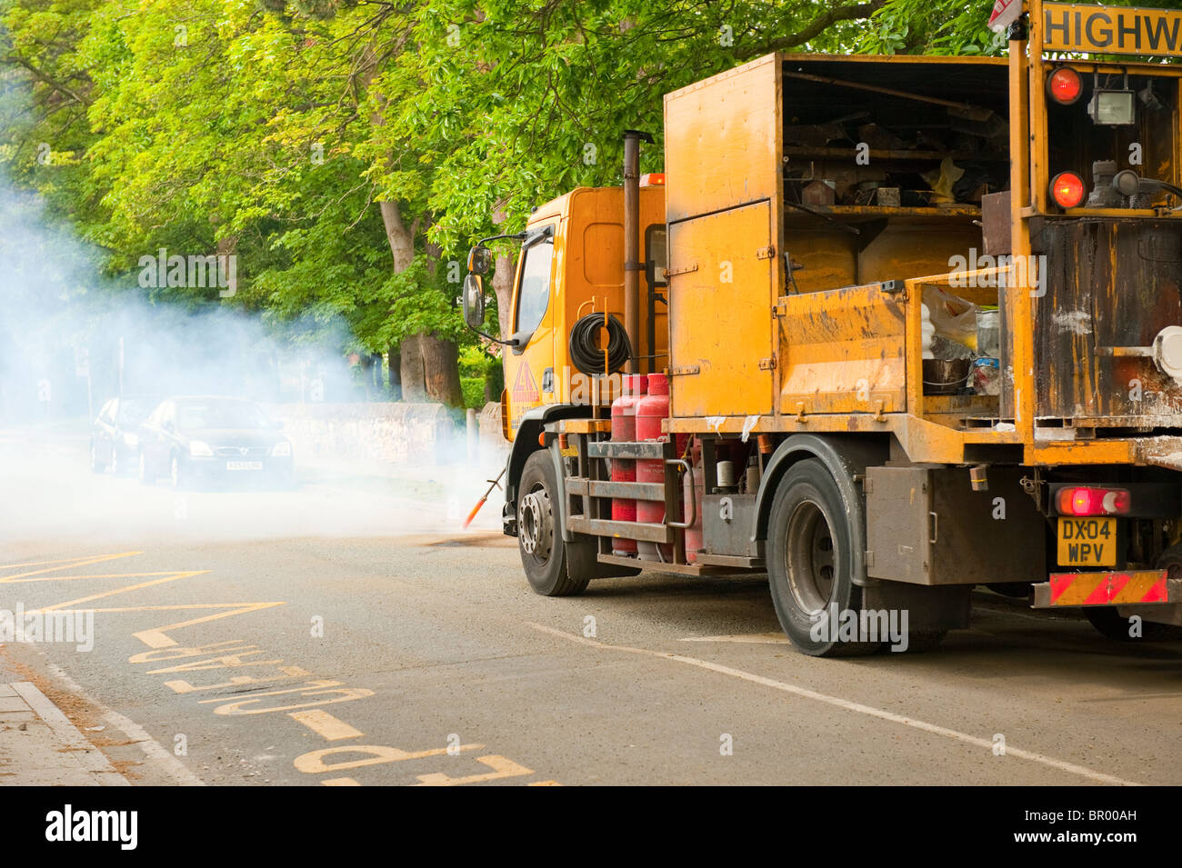 Road marking yellow lines being removed by burning off Stock Photo