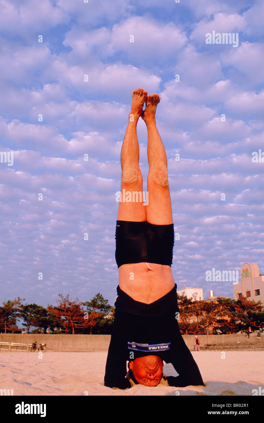 An 84-year-old man follows a daily exercise regimen which includes headstands, yoga, and a swim. Stock Photo