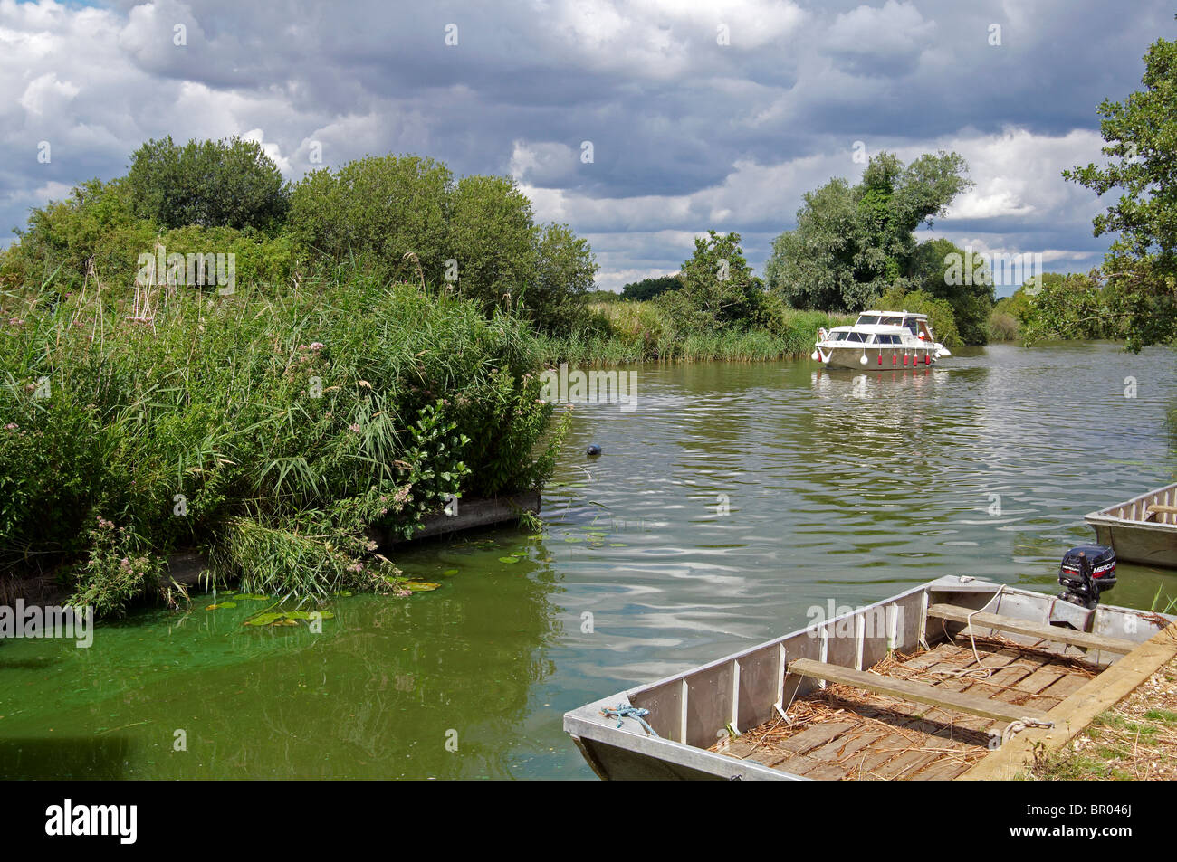 River Ant, part of the Norfolk Broads river system at How Hill with holiday motor cruiser and marshman's punts. Stock Photo