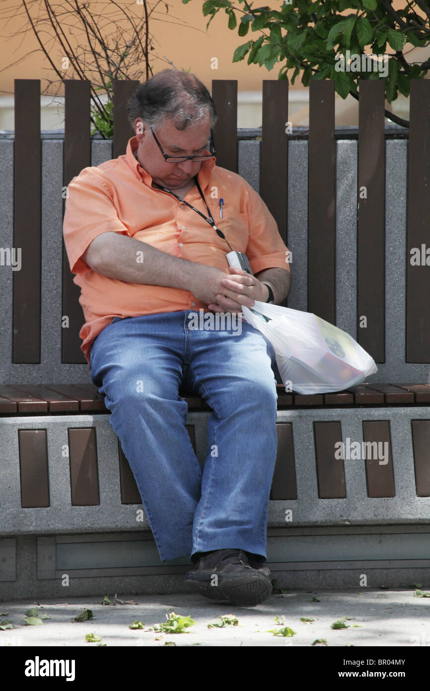 Chubby middle-aged man sat sleeping in public square during siesta in Puigcerda Catalonia Spain Stock Photo