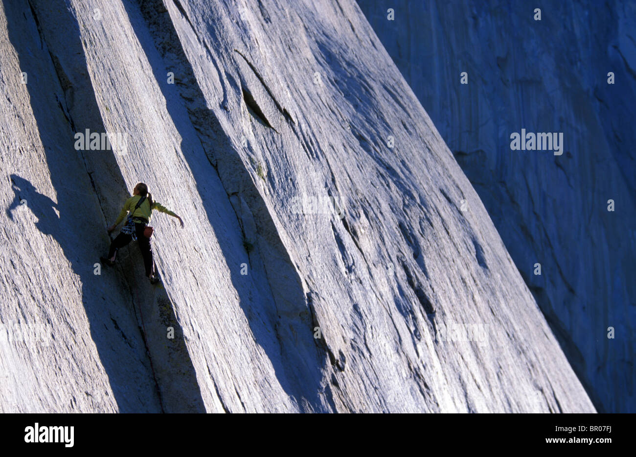 A female rock climber leading climbing a big granite wall in Yosemite National Park. Stock Photo