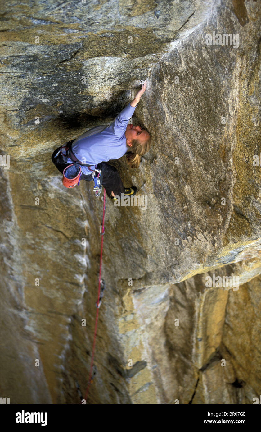 A female rock climber lead climbing on an overhanging granite climbing