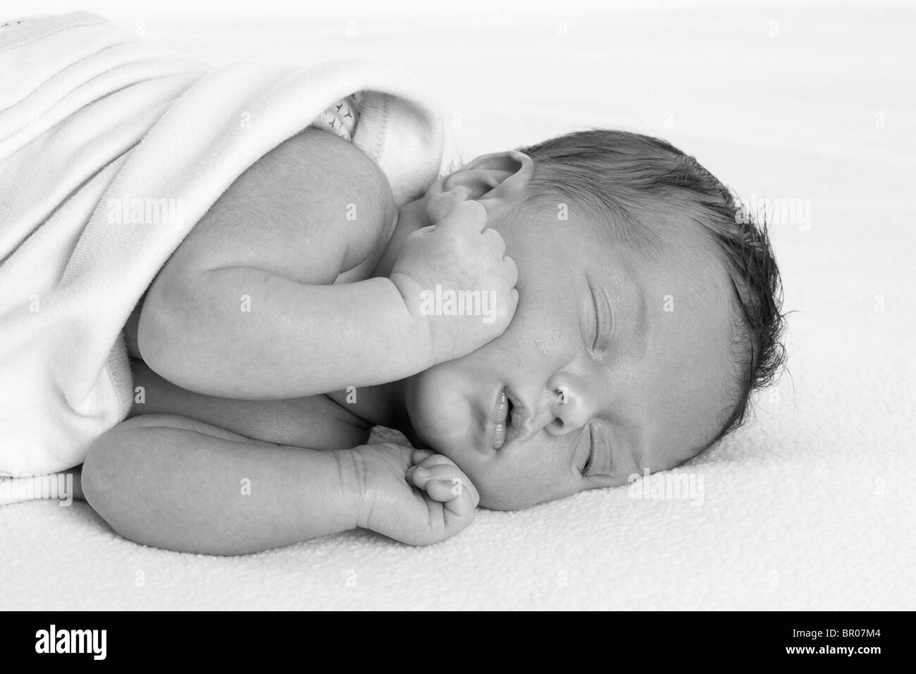 Newborn Caucasian baby rapped in a white blanket on a white background Stock Photo