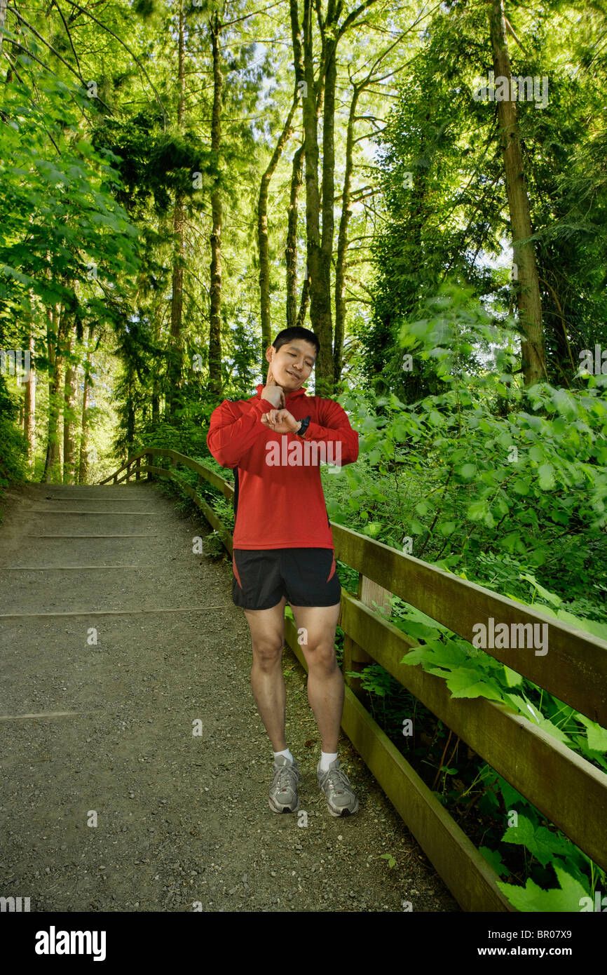 Mixed race man checking pulse after exercise in forest Stock Photo