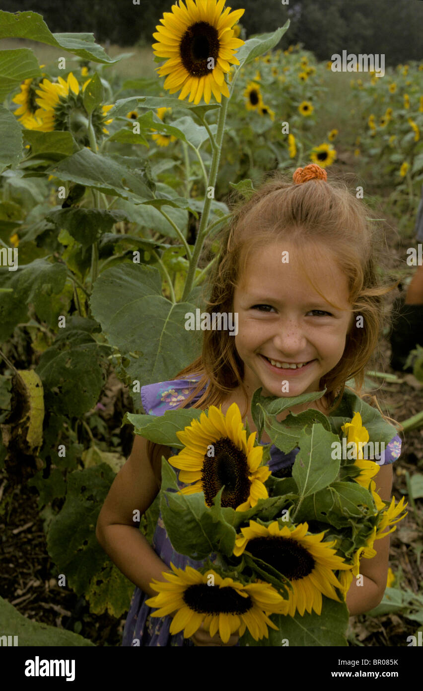 A young red head girls holds a bunch of sunflowers in a flower field ...