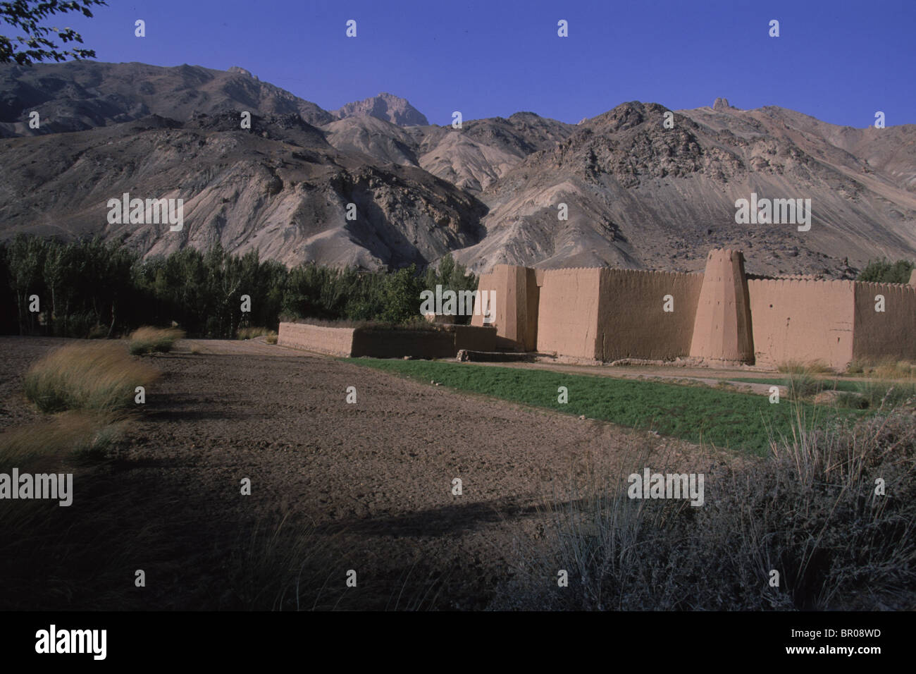 A walled family compound sits below rocky hills, in the Hazarajat, Bamiyan Stock Photo