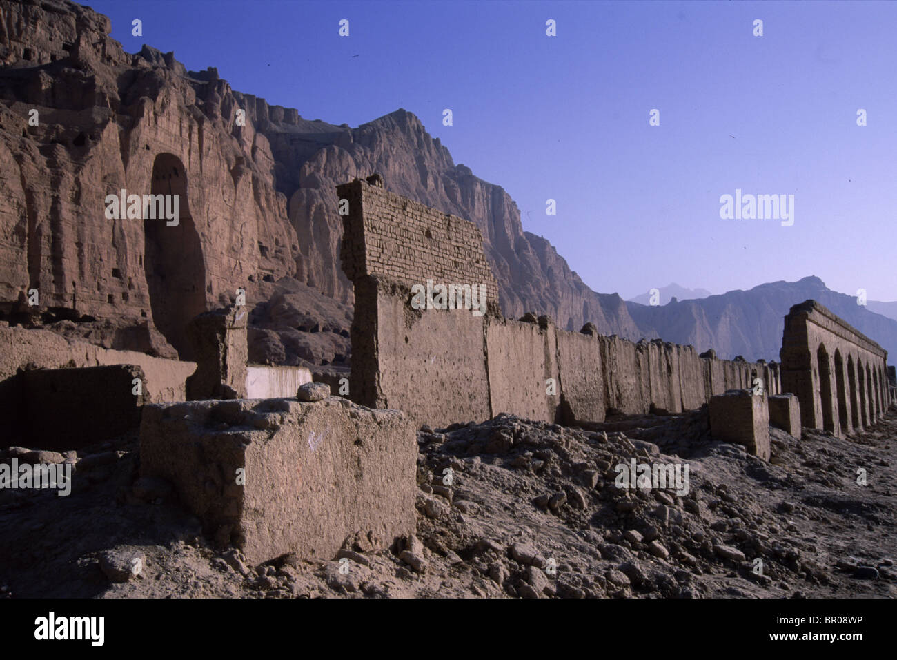The destroyed buildings of the old Bamiyan bazaar frame the empty  niches where one of the famous Buddhas of Bamiyan once stood, Stock Photo