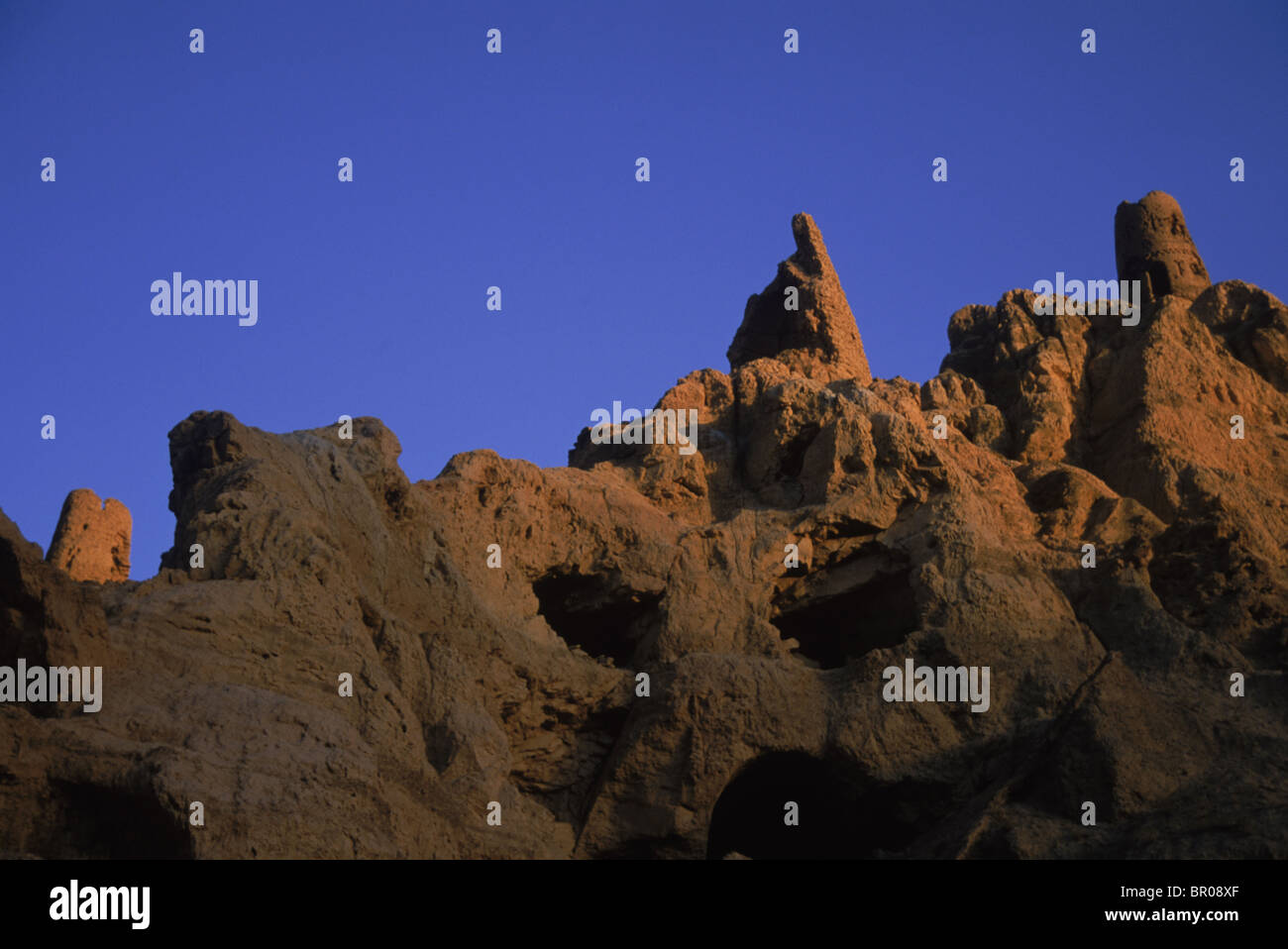 Round stone towers rise over the cliffs which once housed a famous Buddha and Buddhist monastary complex, Bamiyan Valley Stock Photo