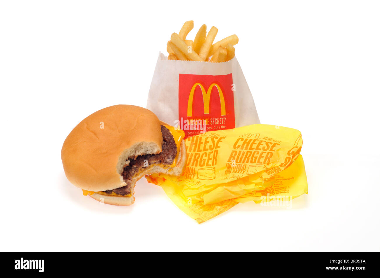 McDonald's cheeseburger with a bite taken on its wrapper and french fries on white background cutout. Stock Photo
