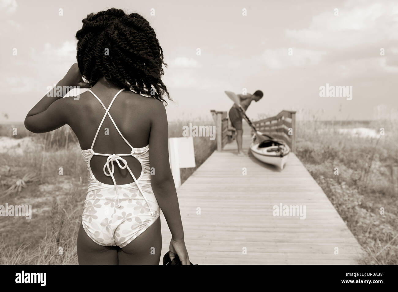 African American girl in swimming suit on Florida beach boardwalk with kayak and father Stock Photo