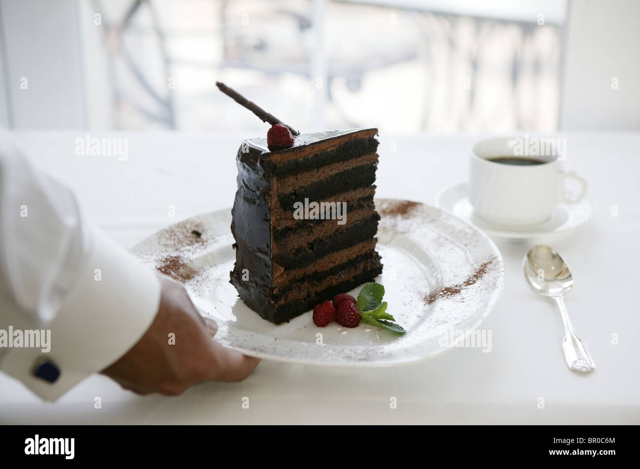 Waiter serving a slice of chocolate cake. Stock Photo