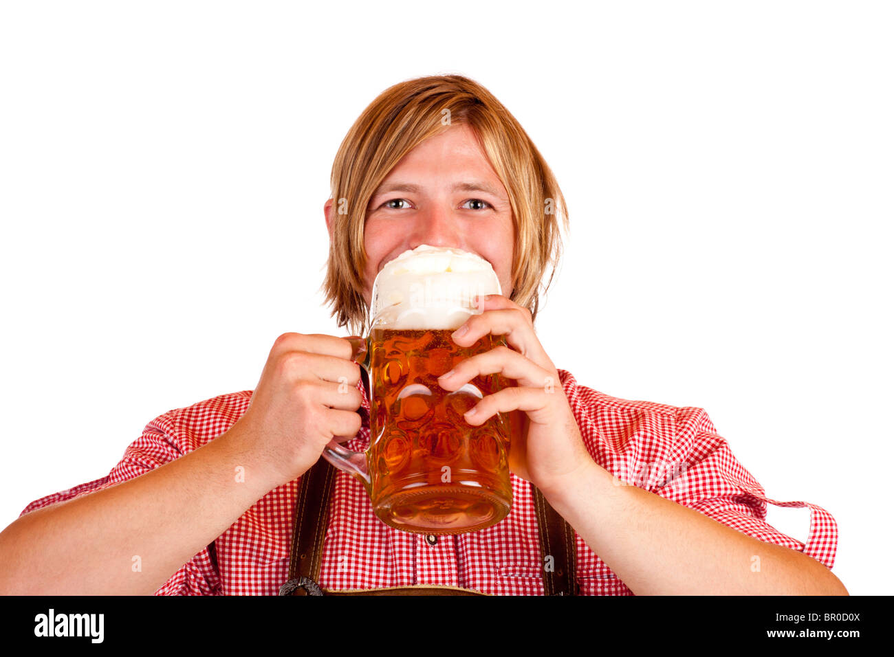 Happy Bavarian man drinks out of Oktoberfest beer stein. Isolated on white background. Stock Photo