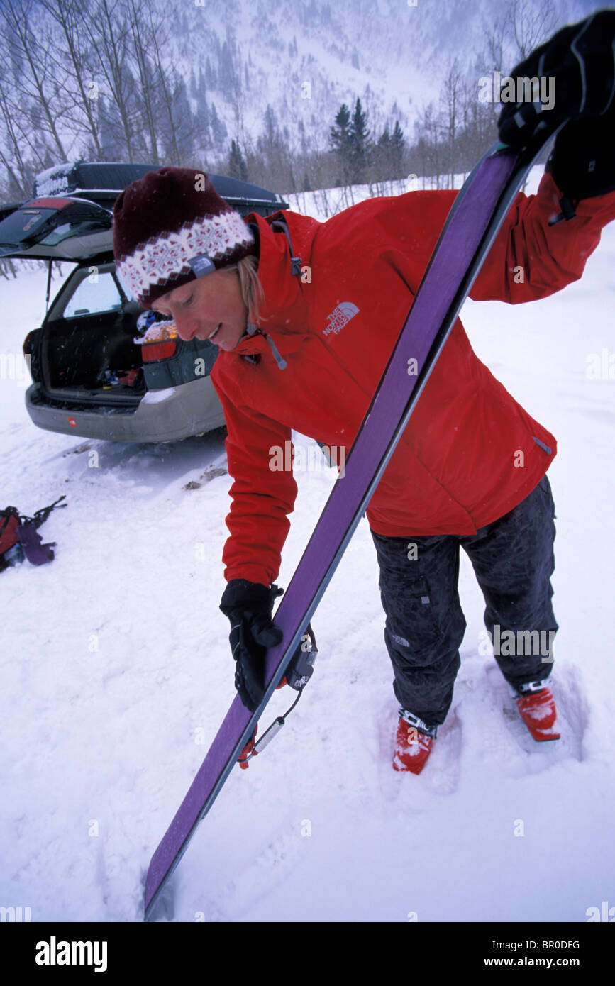 A female telemark skier puts skins on her skis before going skiing in