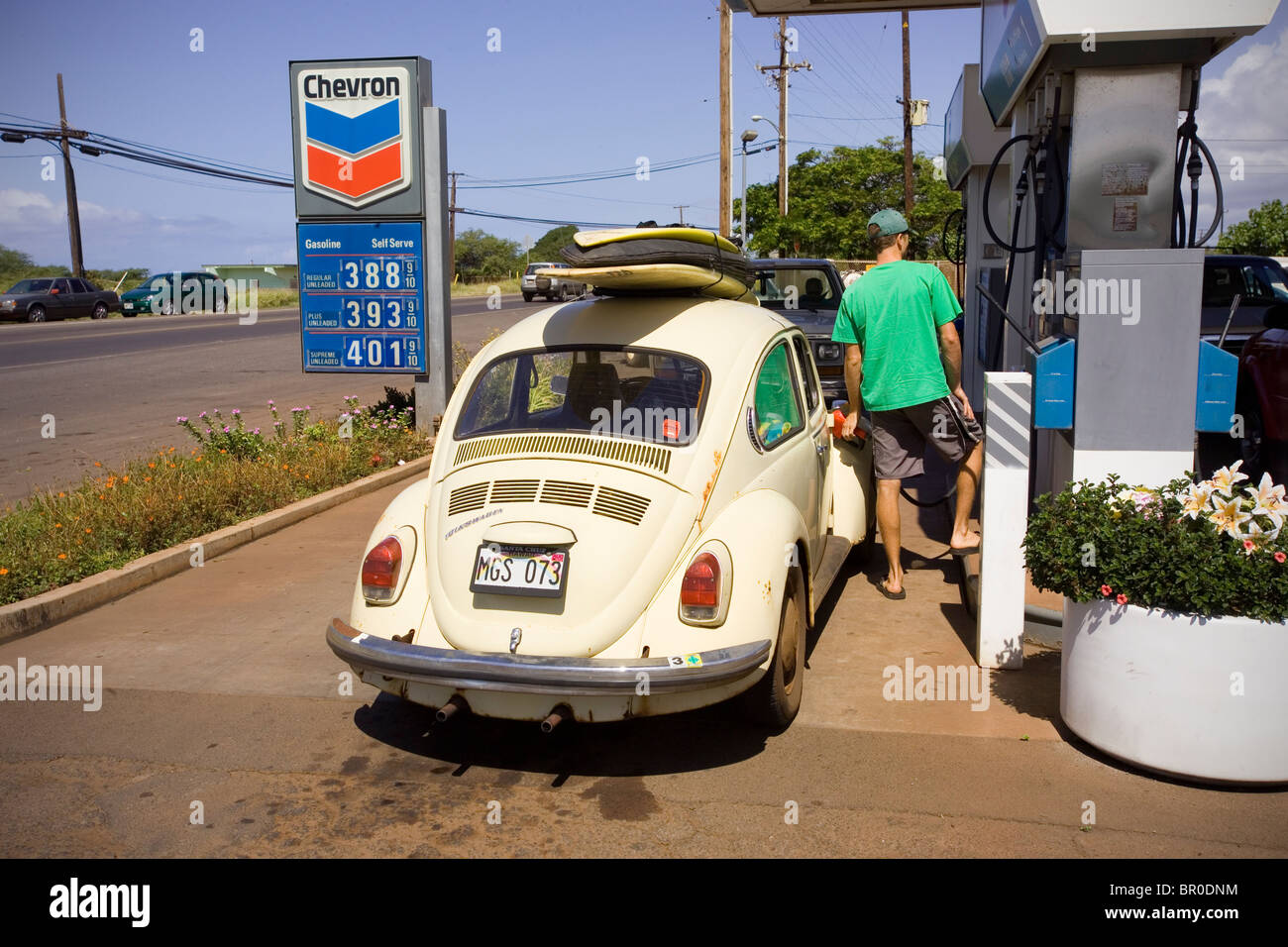 A surfer fills his gas tank with expensive fuel in Kaunakakai, Molokai, Hawaii. Stock Photo