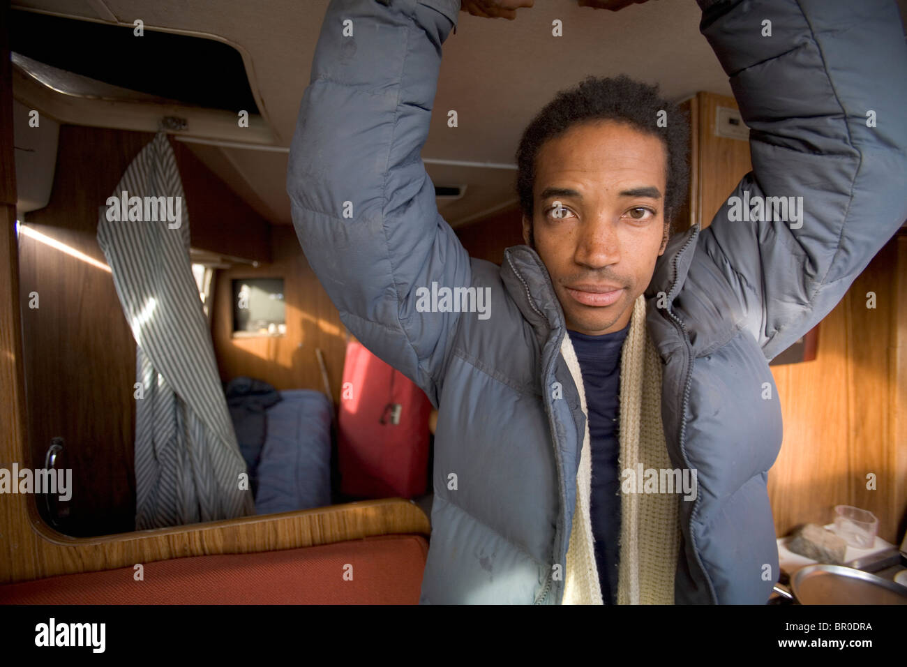 Portrait of black male with hands above his head in a trailer. Stock Photo