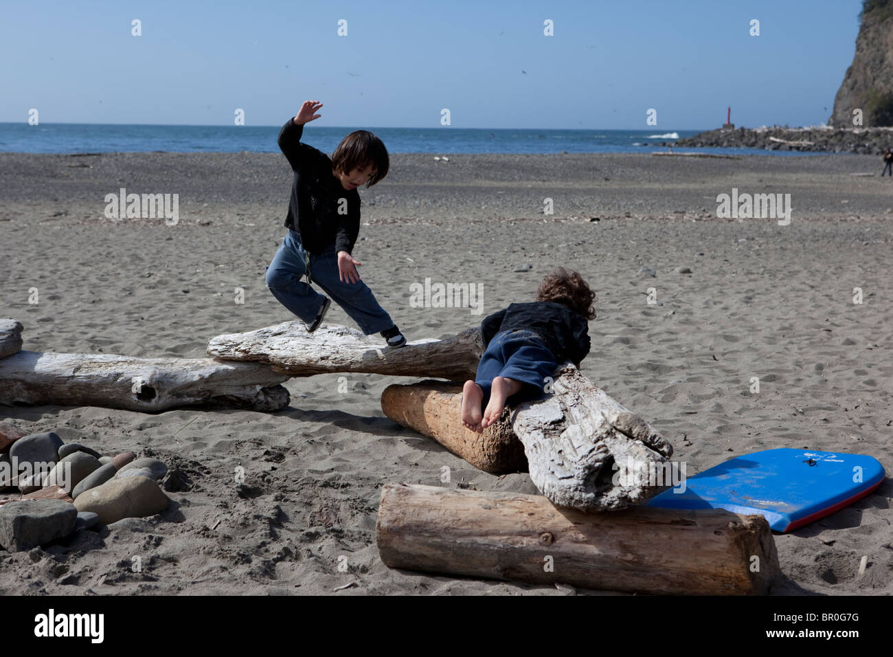 two young boys playing on beach logs in the pacific northwest Stock ...