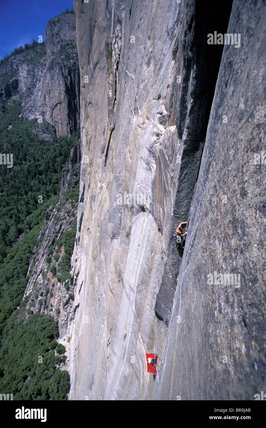A woman belays a man rock climbing from a porta ledge on a big wall