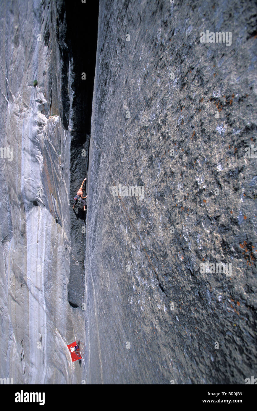 A woman belays a man rock climbing from a porta ledge on a big wall